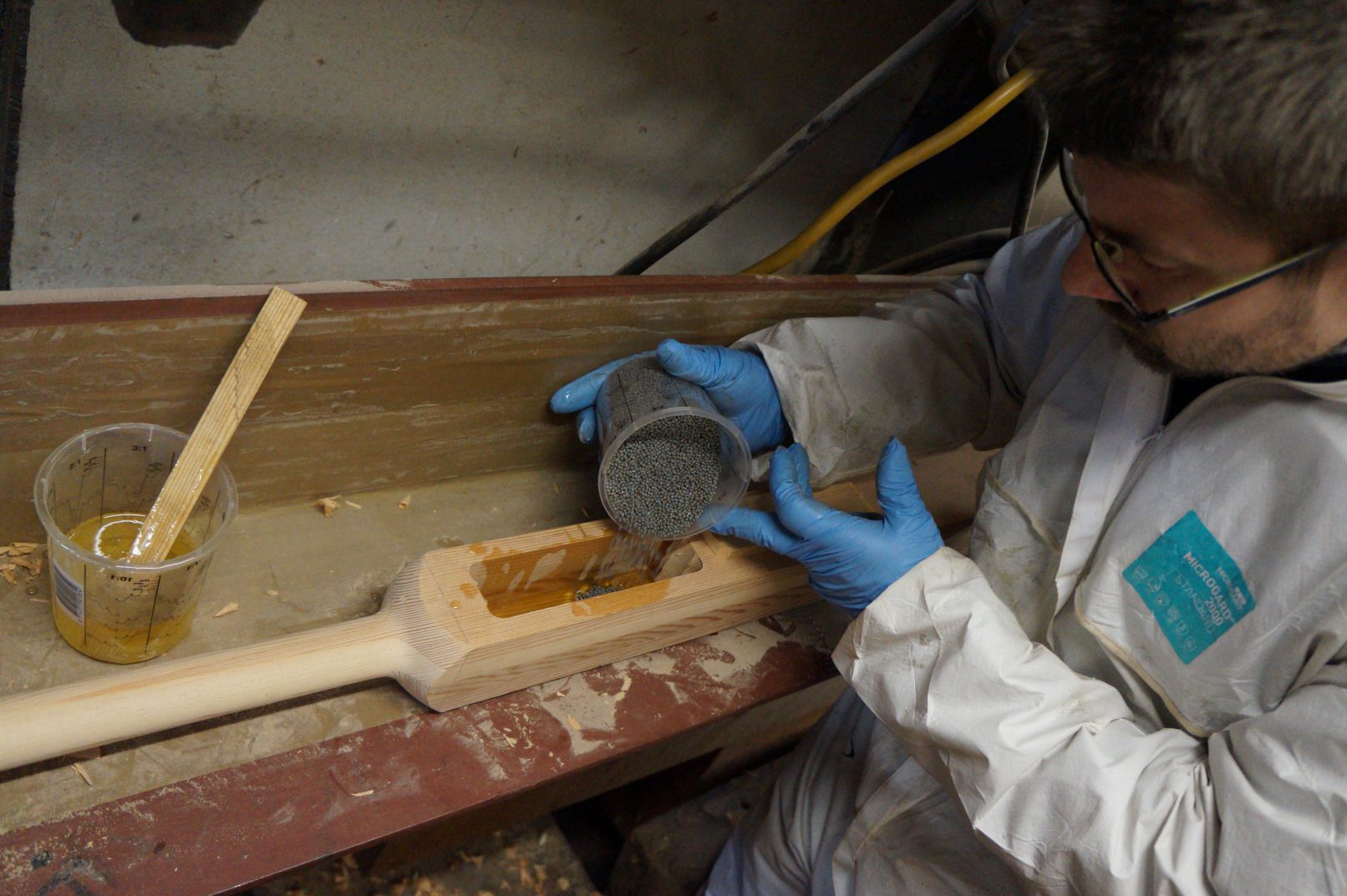 Scheepstimmerman giet loden korrels in cassette van roeiriem