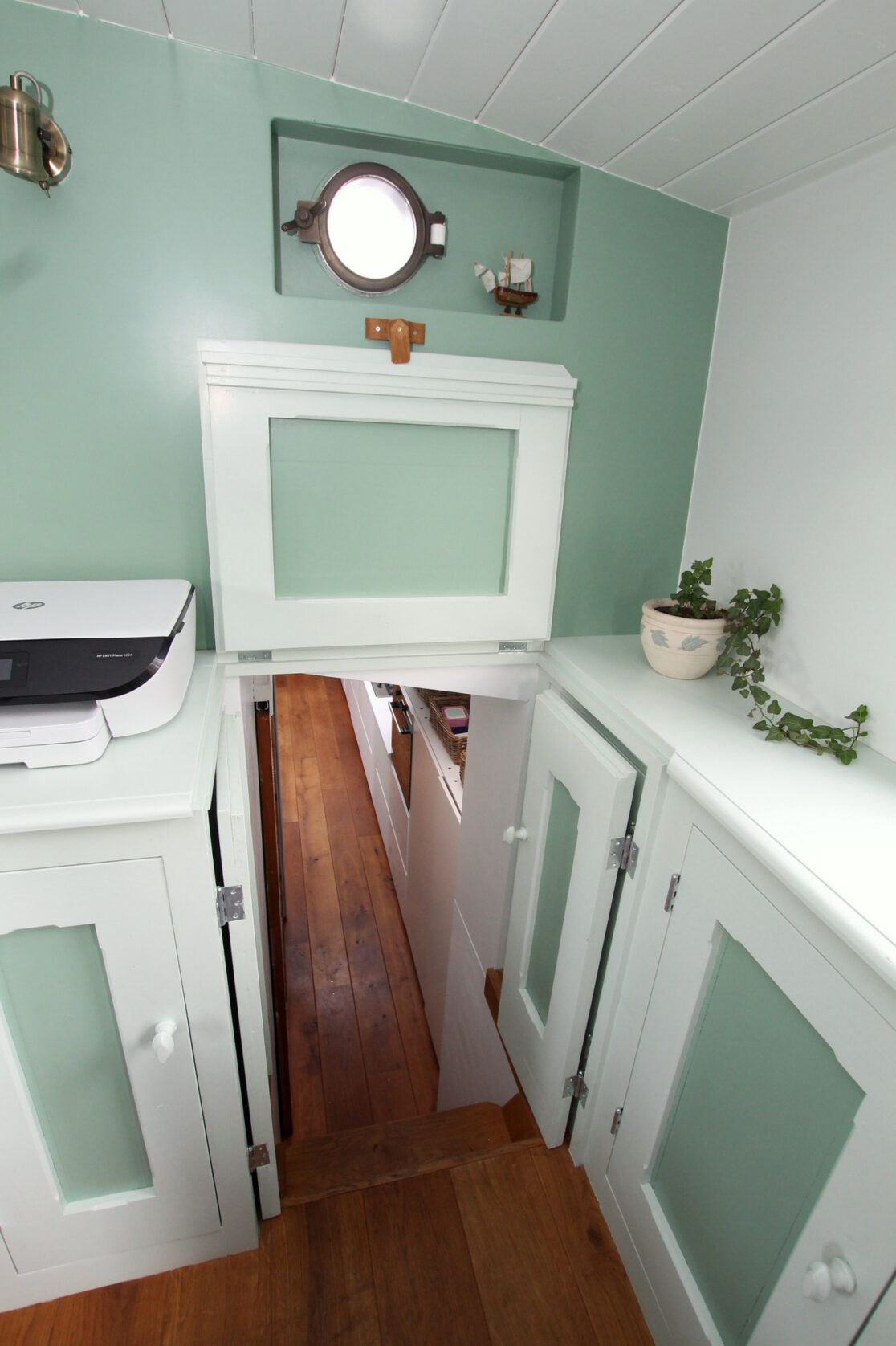 Doorgang in een woonschip met paneelwerk in wit en groen