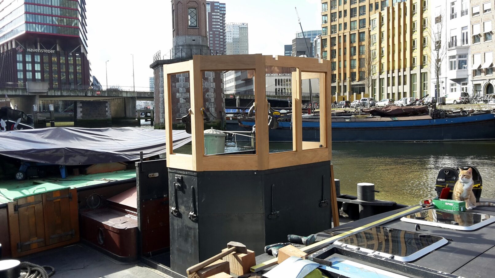 Stuurhut in aanbouw op beurtschip, met kat aan dek